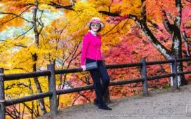A stylish mature woman poses in front of vibrant autumn maple trees in Korankei Park, Aichi, Japan. | โครันเค (Korankei / 香嵐渓)