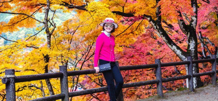 A stylish mature woman poses in front of vibrant autumn maple trees in Korankei Park, Aichi, Japan. | โครันเค (Korankei / 香嵐渓)