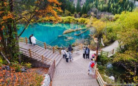 Tourists visit Jiuzhaigou Valley National Park, Sichuan, China, on October 21, 2023, enjoying autumn foliage and clear turquoise lakes along wooden walkways.
