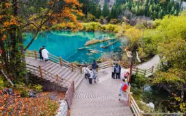 Tourists visit Jiuzhaigou Valley National Park, Sichuan, China, on October 21, 2023, enjoying autumn foliage and clear turquoise lakes along wooden walkways.